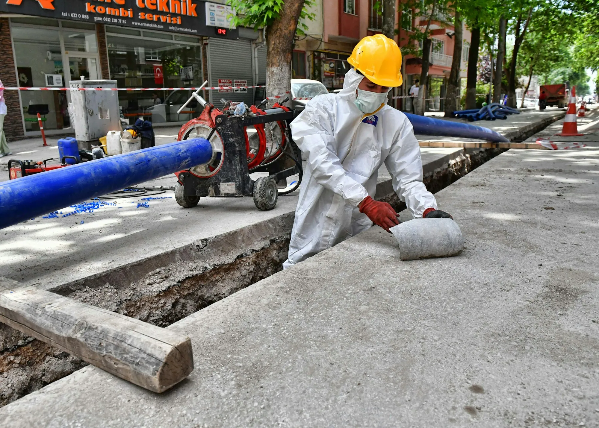 Worker in a protective suit rolling out sheeting at a work zone
